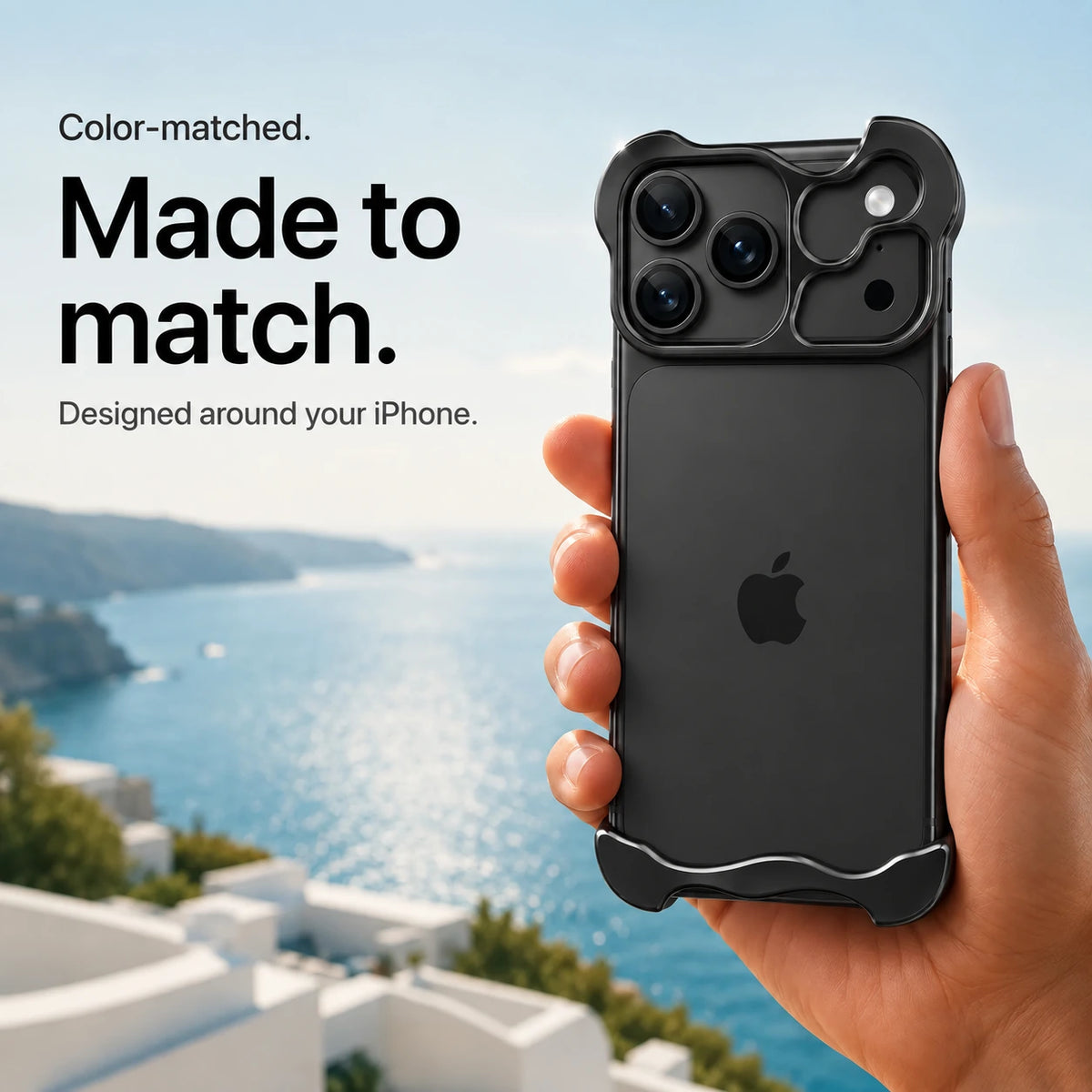 Black sculpted metal phone case held in a hand above a coastal background #color_Midnight Black