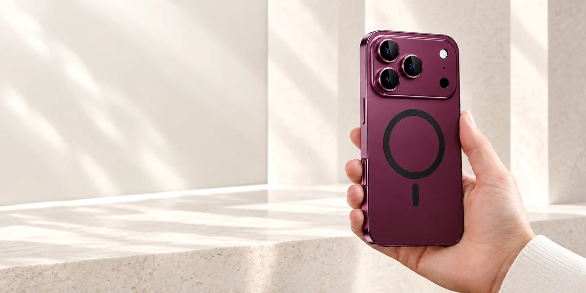 Dark cherry metal phone case held in a bright stone interior, showing the matching back, camera surround and magnetic ring.