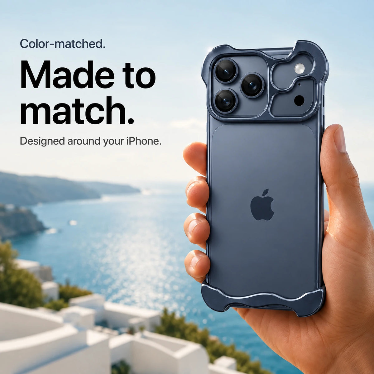 Navy blue sculpted metal phone case held in a hand above a coastal background #color_Deep Blue