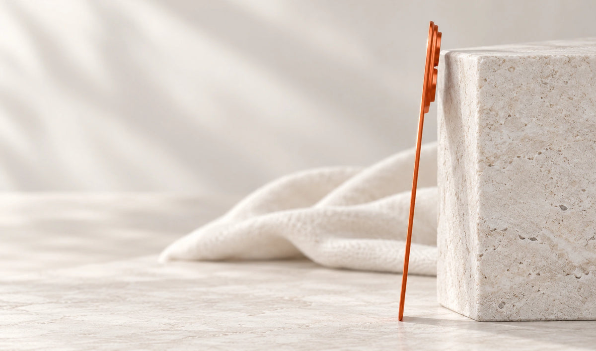 Edge view of a thin orange backplate leaning against a pale stone ledge.