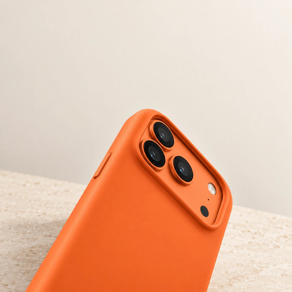 Close-up of the orange silicone case's raised border around the wide three-lens camera area.