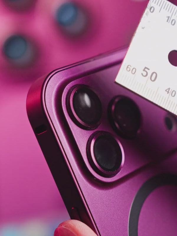 Metal ruler passing across the raised camera guard on a dark cherry phone case